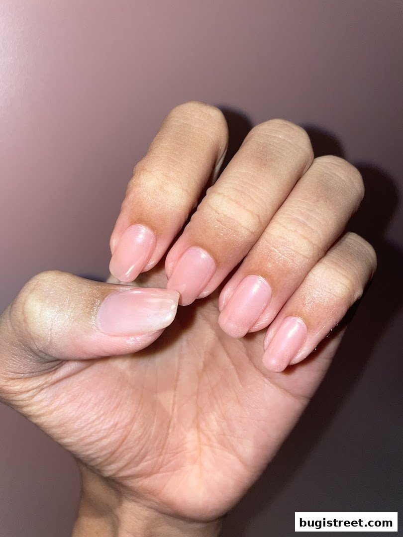 A close-up shot of a hand with perfectly manicured, light pink nails.