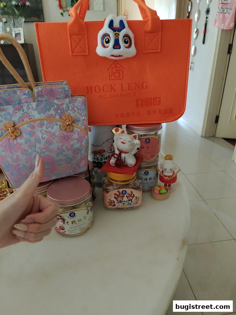 A collection of festive gift items, including bags and jars of snacks, with a lucky cat figurine.