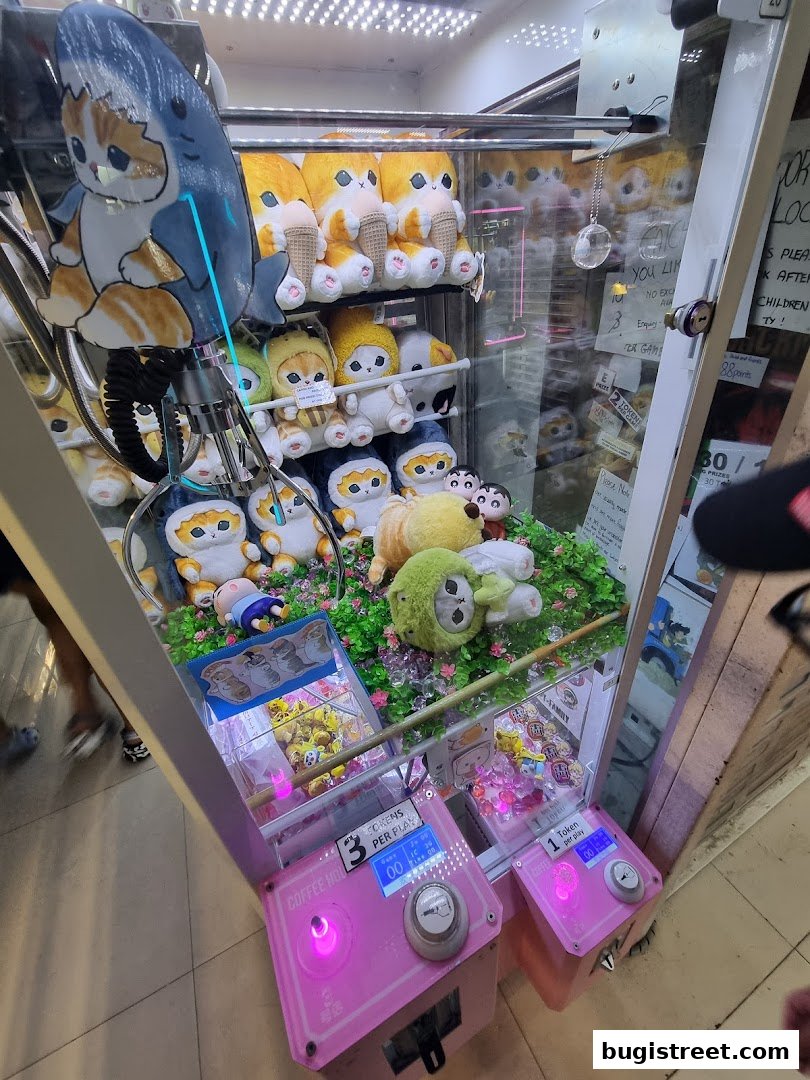 A pink claw machine filled with cute plush toys, including cats and a shark.