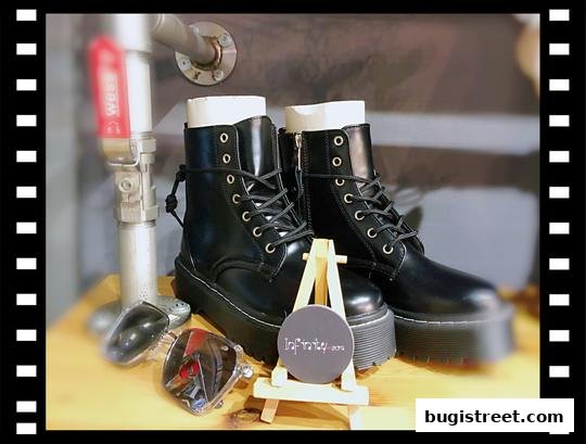 A pair of black combat boots displayed with accessories and a shop logo.