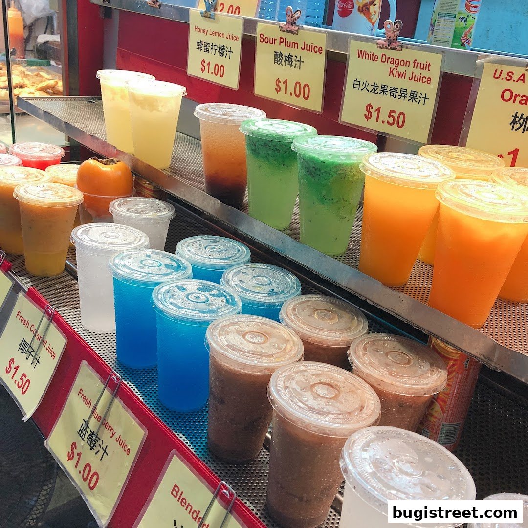 A display of various fresh fruit juices and blended drinks in clear plastic cups with price tags.