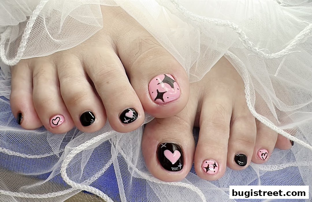 Close-up of feet with stylish pink and black toenail art featuring hearts and stars.