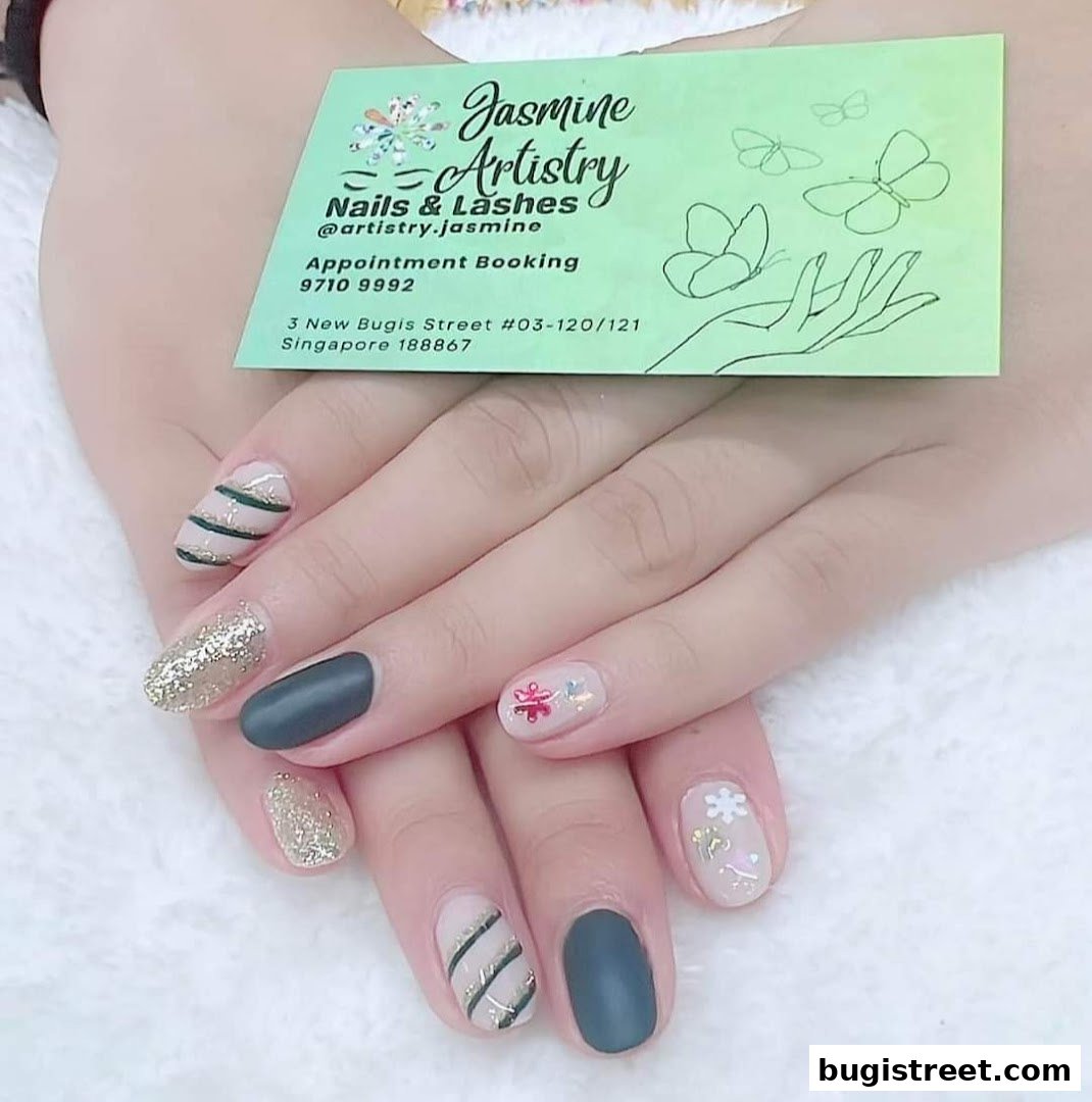 A close-up of hands with beautifully designed nails, featuring glitter and striped patterns.