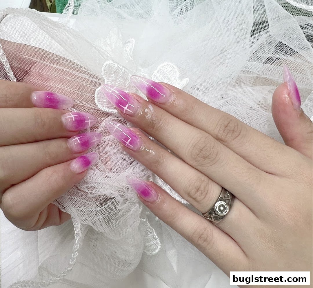 Close-up of hands with stylish pink and white gradient nails featuring a white grid design.