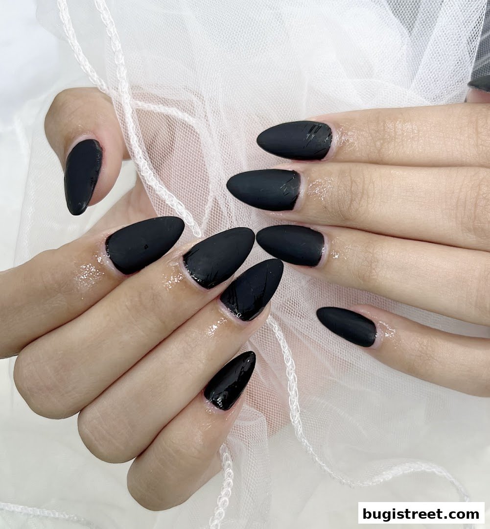 Close-up of hands with matte and glossy black almond-shaped nails.