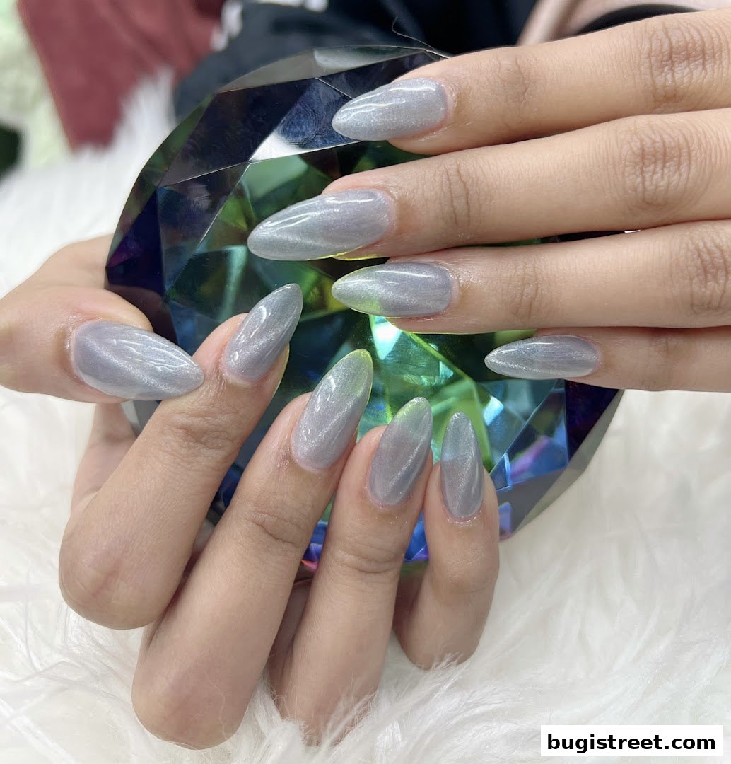 Close-up of hands with elegant, shimmering grey almond-shaped nails.