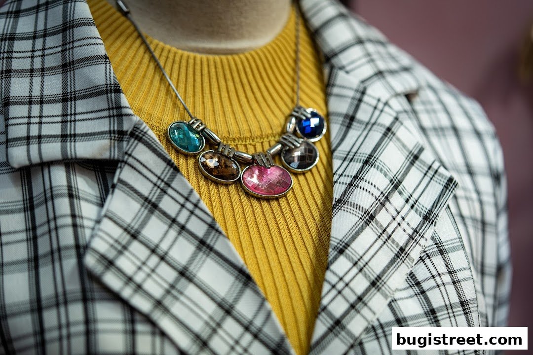 A close-up of a mannequin wearing a yellow ribbed top and a plaid blazer with a statement necklace.