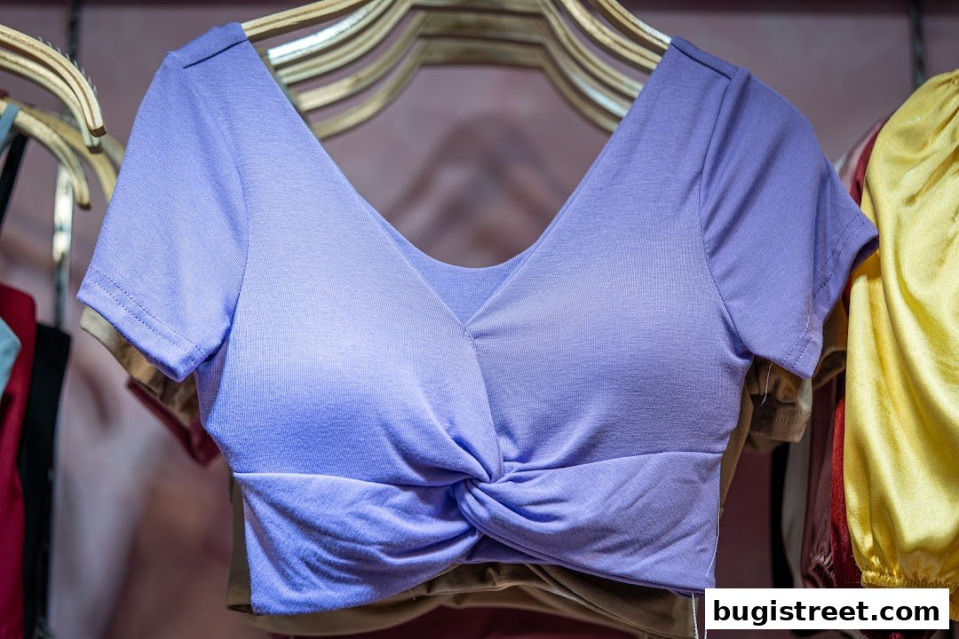 A close-up of a lavender twisted crop top hanging on a wooden hanger.