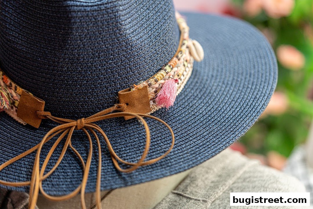 Close-up of a stylish blue straw hat with a decorative band featuring tassels and shells.