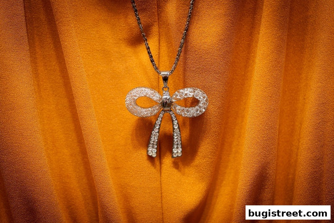 A close-up of a sparkling bow pendant necklace on an orange fabric.