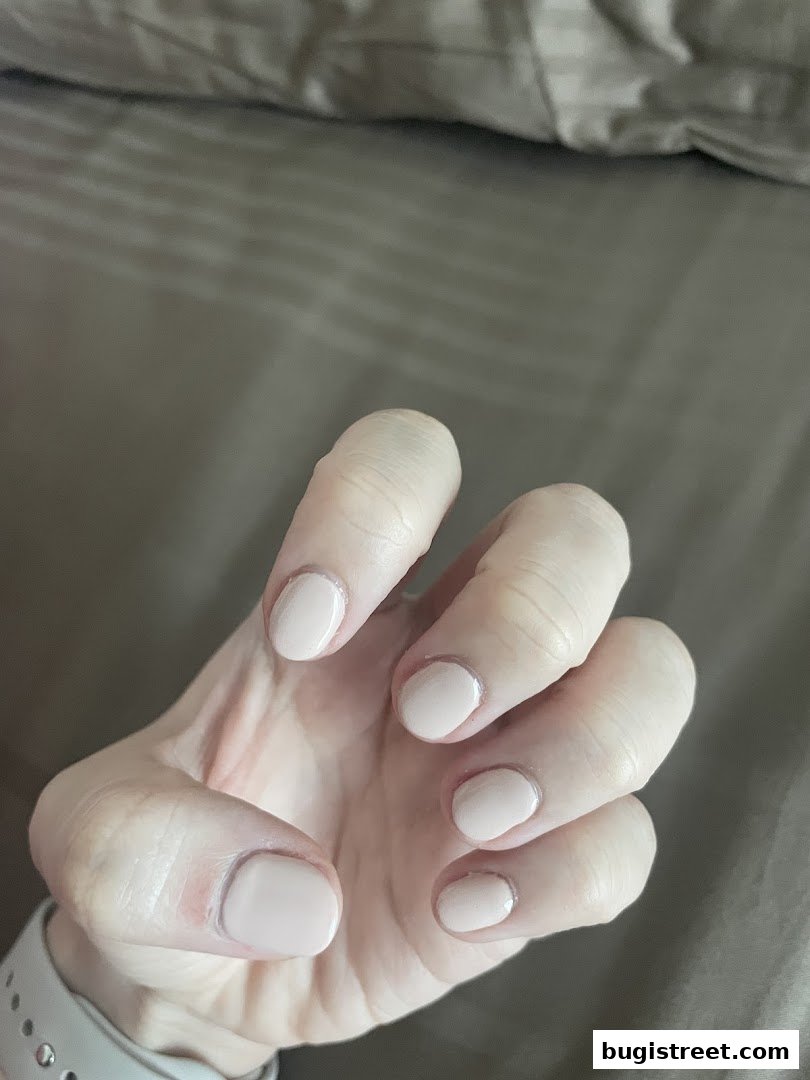 A close-up shot of a hand with perfectly manicured, light pink nails.
