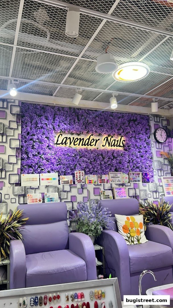 Interior of Lavender Nails salon with purple chairs, floral wall, and nail display.