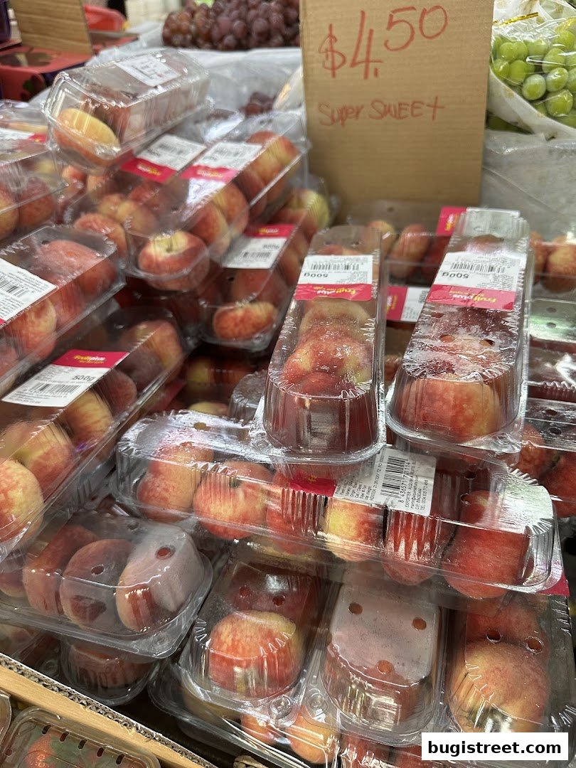 A display of fresh, pre-packaged fruits, including peaches and grapes, with a price sign.