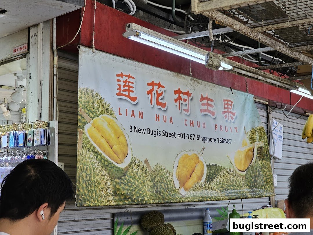 A banner for Lian Hua Chun Fruit shop displaying durians and shop details.