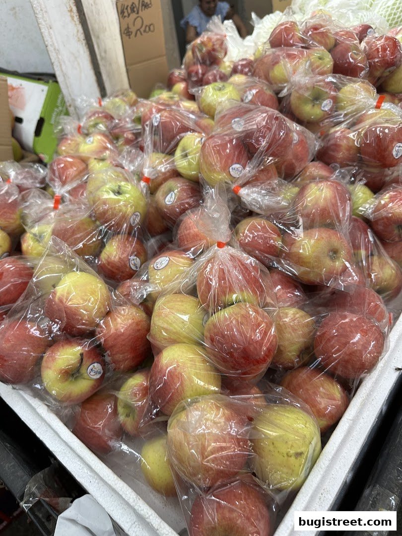 A display of fresh apples, many individually packaged, at a fruit stall.