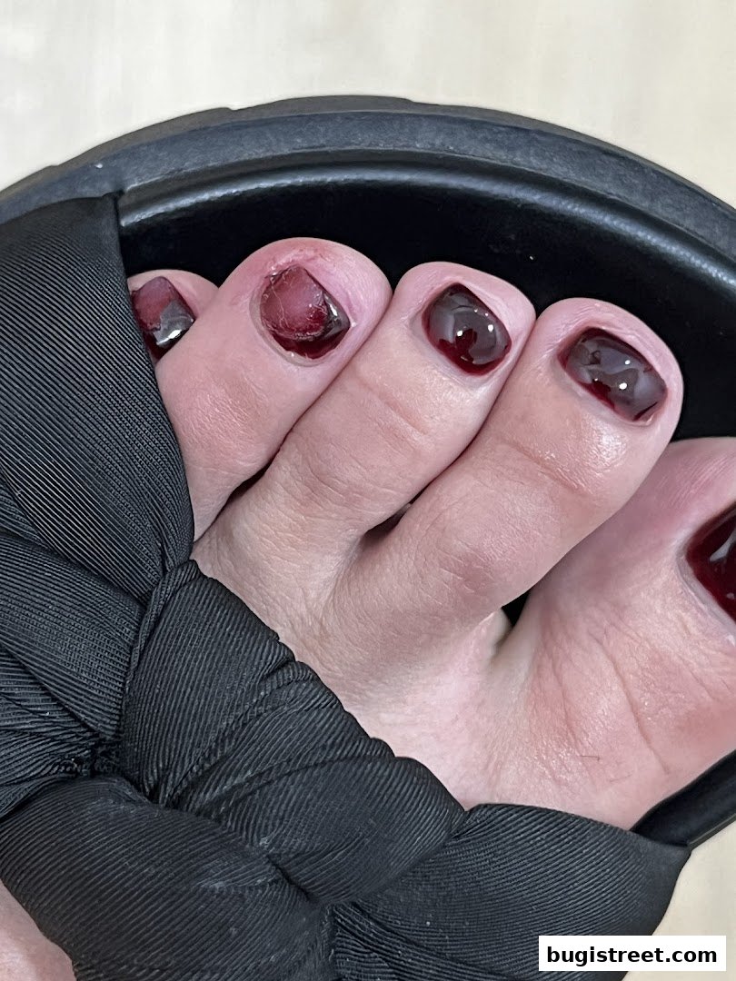 Close-up of toes with dark red nail polish and a black sandal strap.