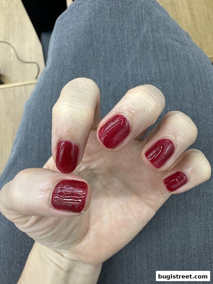 A close-up of a hand with perfectly manicured, glossy dark red nails.
