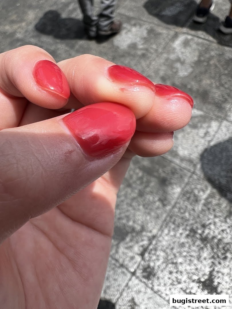 Close-up of a hand with vibrant red gel nails.