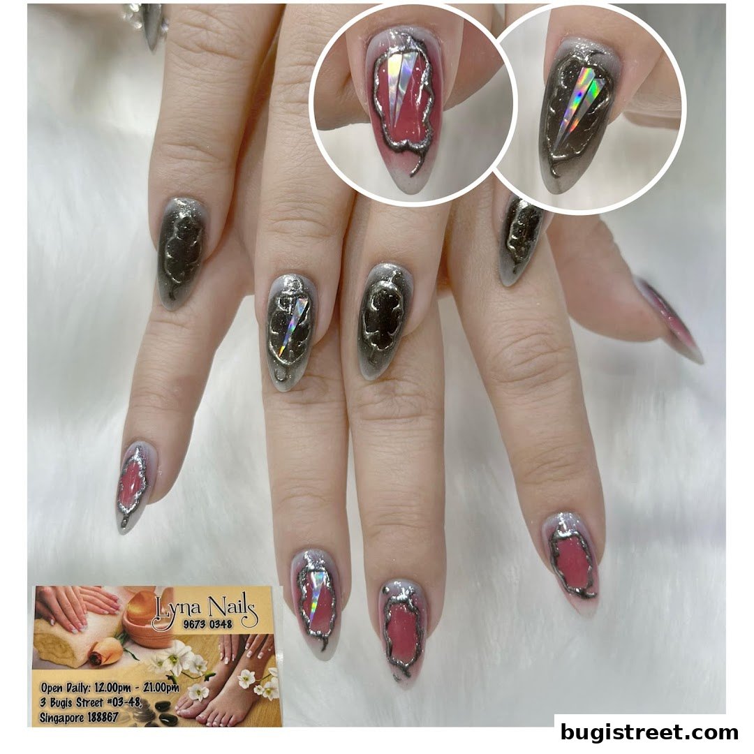 Close-up of hands with intricate, artistic nail designs featuring metallic accents and gemstone-like details.