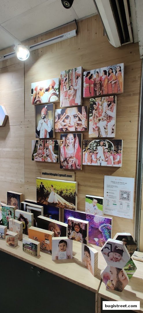 A display of various photo prints on wooden blocks, showcasing portraits and event photography.