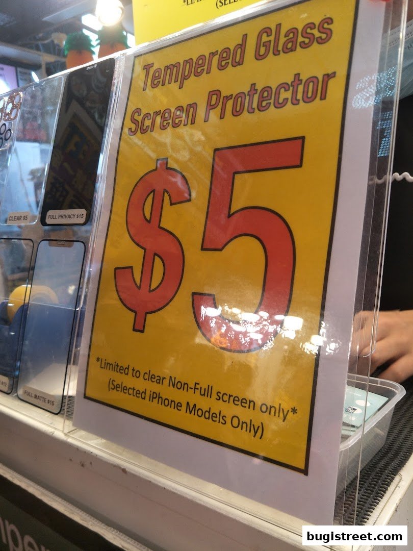 A sign advertising tempered glass screen protectors for $5, with other options available.