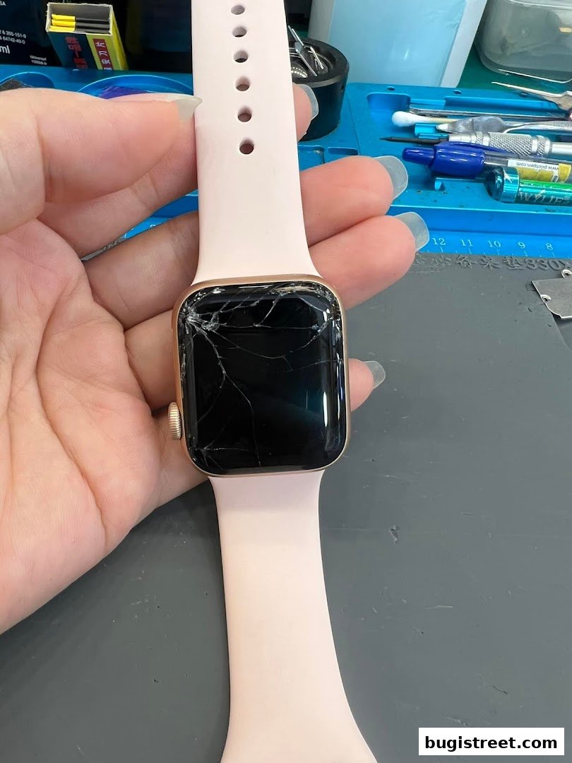 A hand holds a cracked Apple Watch with a pink band, ready for repair.
