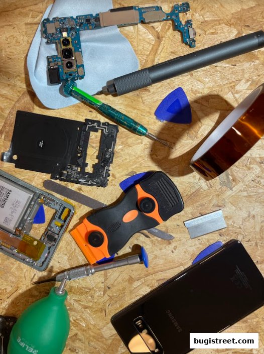 Mobile phone repair tools and disassembled phone parts laid out on a wooden surface.