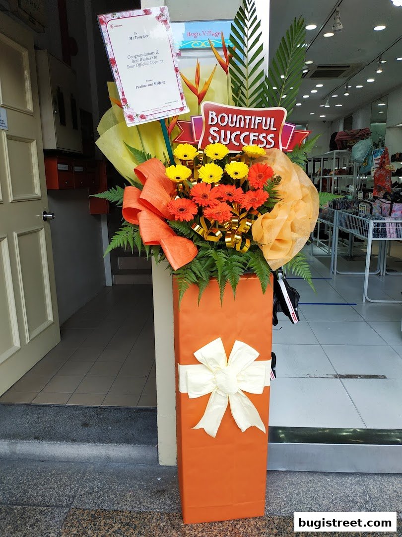 A floral arrangement with a congratulatory message outside a shop called Moda Boutique.
