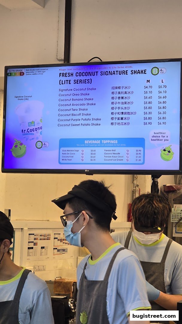 A digital menu board displays various fresh coconut signature shakes and beverage toppings.