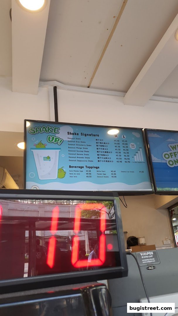 A menu board displaying various coconut shakes and beverage toppings with prices.