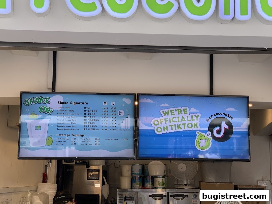 A digital menu board displaying various coconut shakes and beverage toppings with prices.