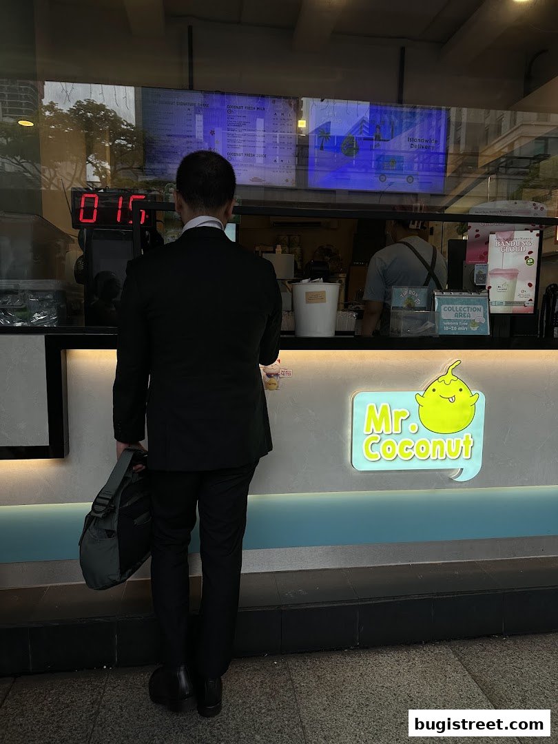 A man in a suit stands in front of the Mr. Coconut shop counter.