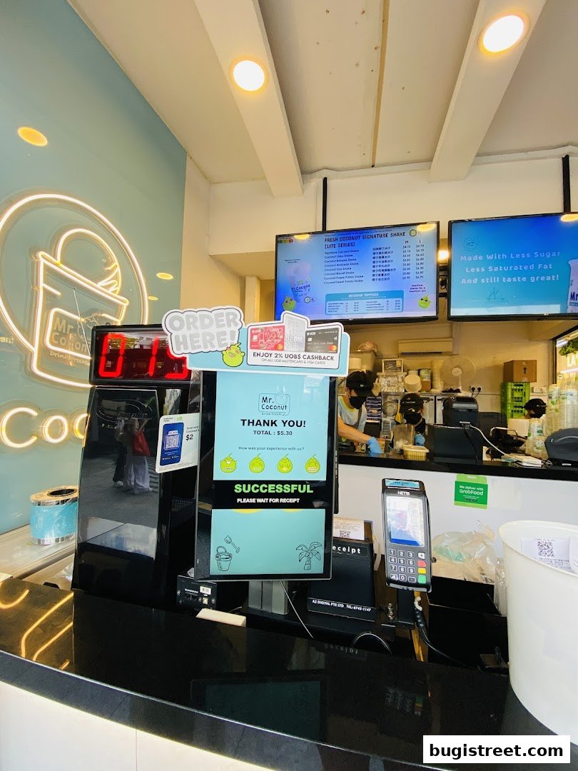 A counter at Mr. Coconut with a digital order screen, menu, and payment terminal.