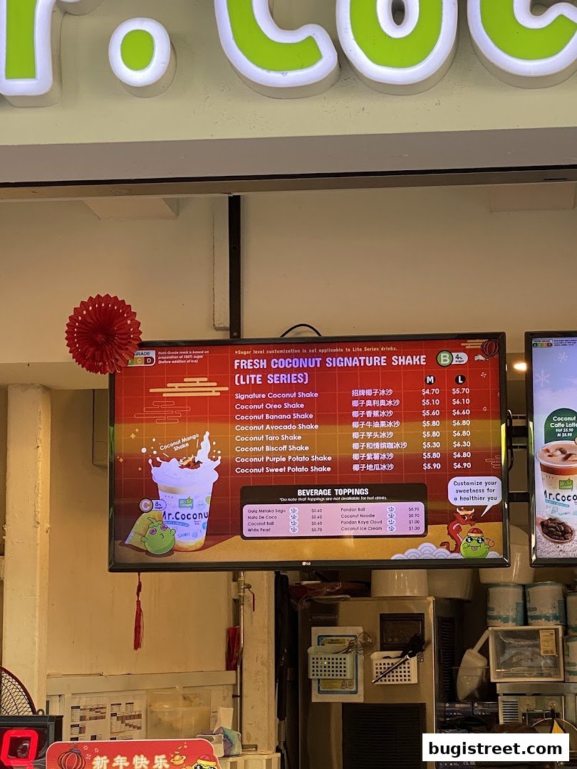 A digital menu board displays various fresh coconut shakes and beverage toppings at Mr. Coconut.