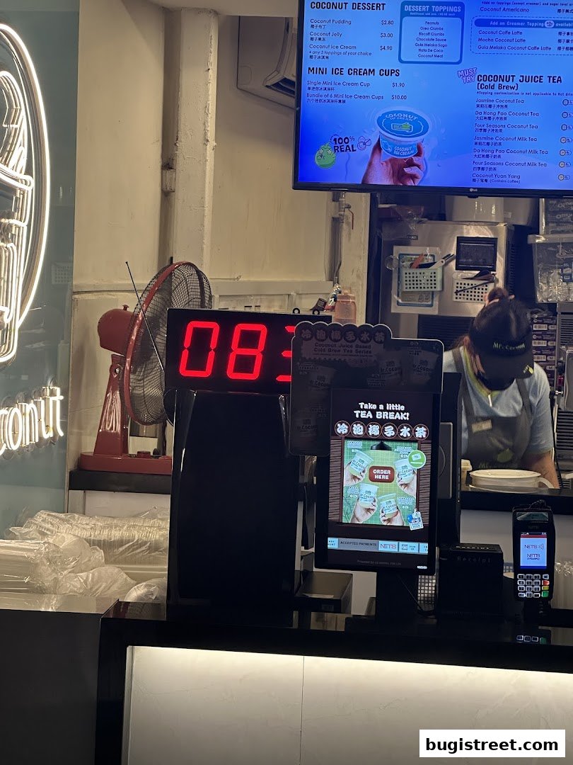 A digital menu board displaying coconut desserts, ice cream cups, and juice teas with prices.
