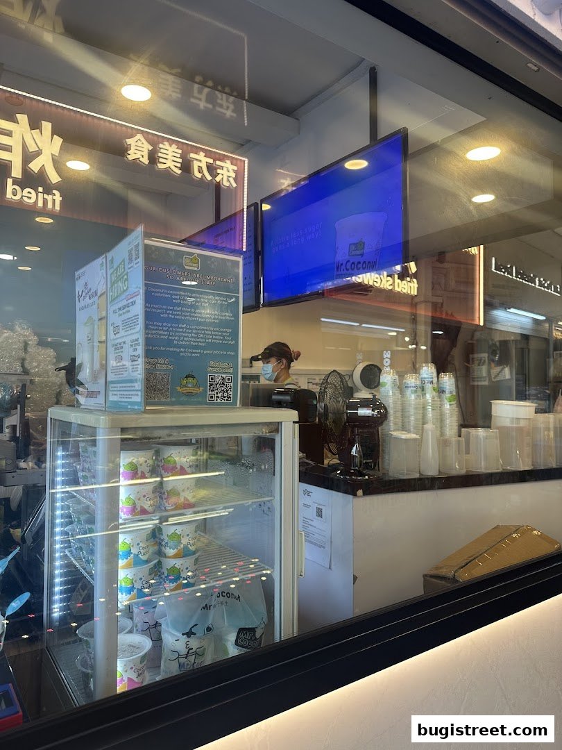 View of a Mr. Coconut shop counter with drinks, a fridge, and a hiring sign.