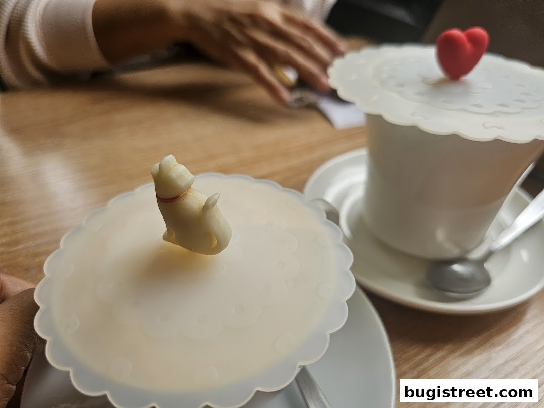 Two cups with decorative silicone lids, one with a cat and the other with a heart.