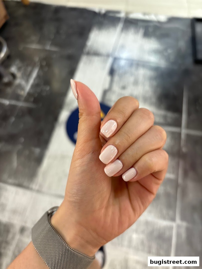 A hand with perfectly manicured, light pink nails gives a thumbs up.
