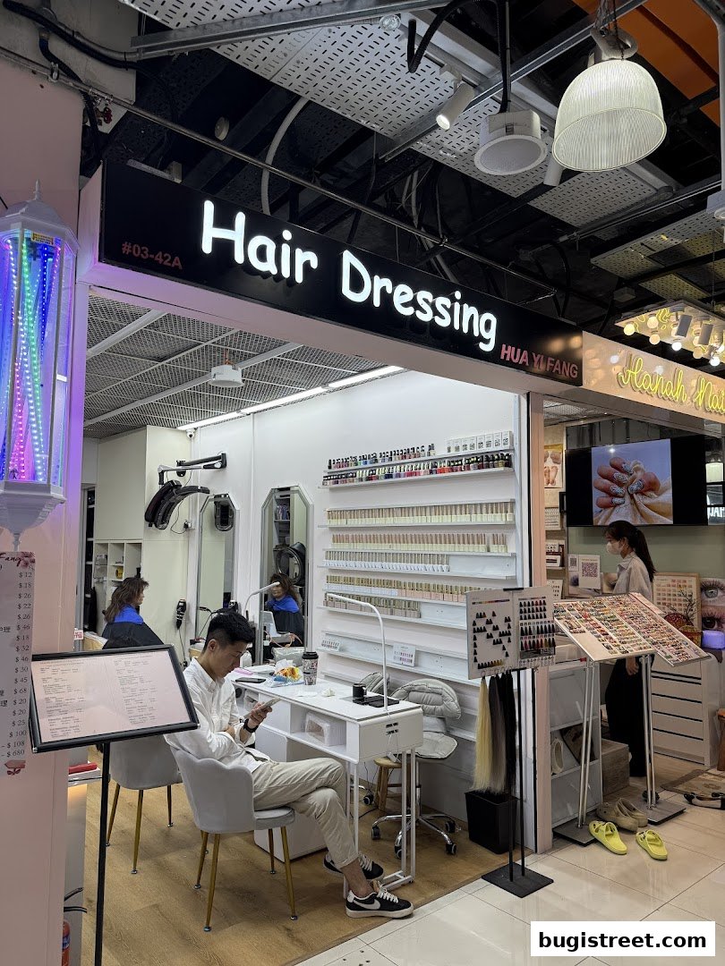 Nails By Hua Yi Fang salon interior with nail technicians and displays of nail polish.