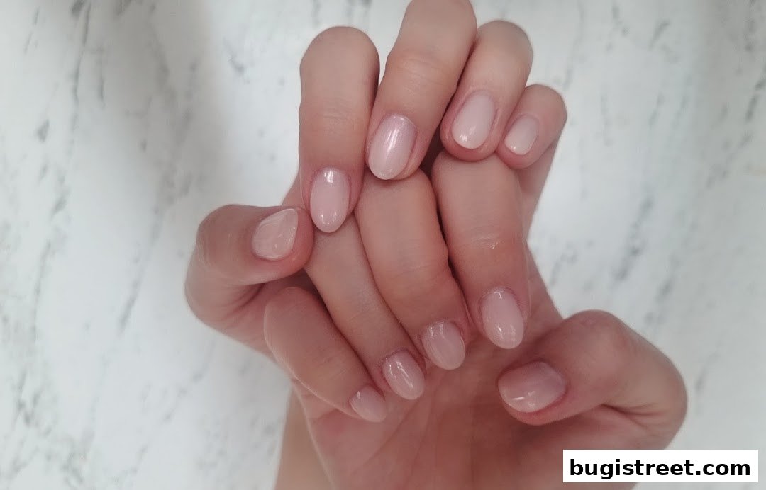 Close-up of hands with perfectly manicured, natural-looking light pink gel nails.