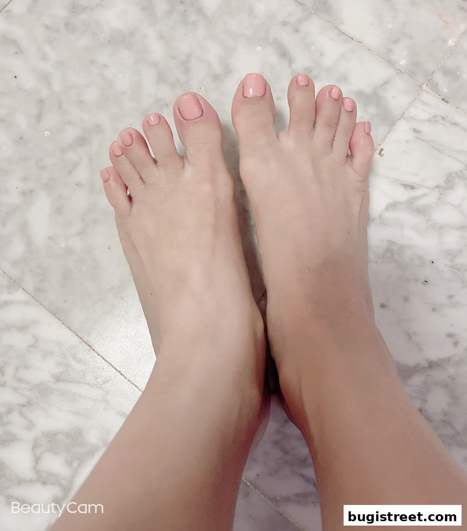 A close-up shot of a person's feet with neatly painted light pink toenails.