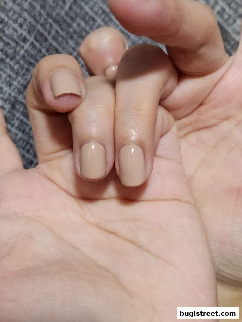 Close-up of a hand with neatly manicured nails painted in a neutral beige shade.