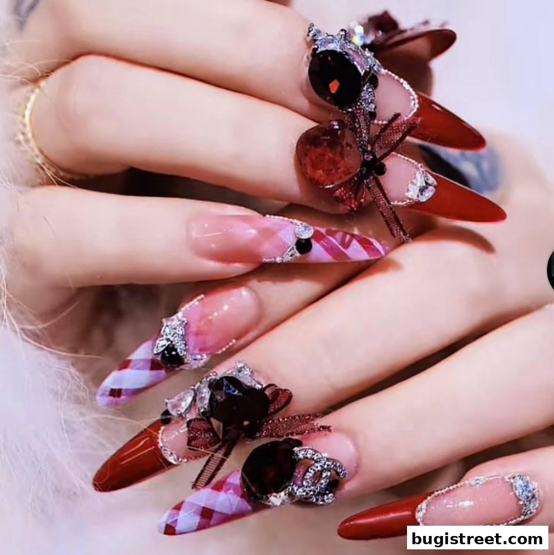 Close-up of hands with elaborately decorated, long, pointed nails featuring red polish, rhinestones, and bows.