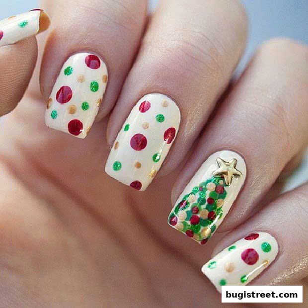 Close-up of a hand with festive Christmas-themed nail art, featuring polka dots and a Christmas tree.