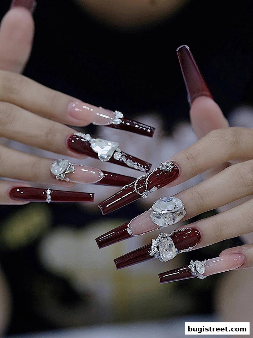 Close-up of hands with elaborate, long, coffin-shaped nails adorned with gems and intricate designs.