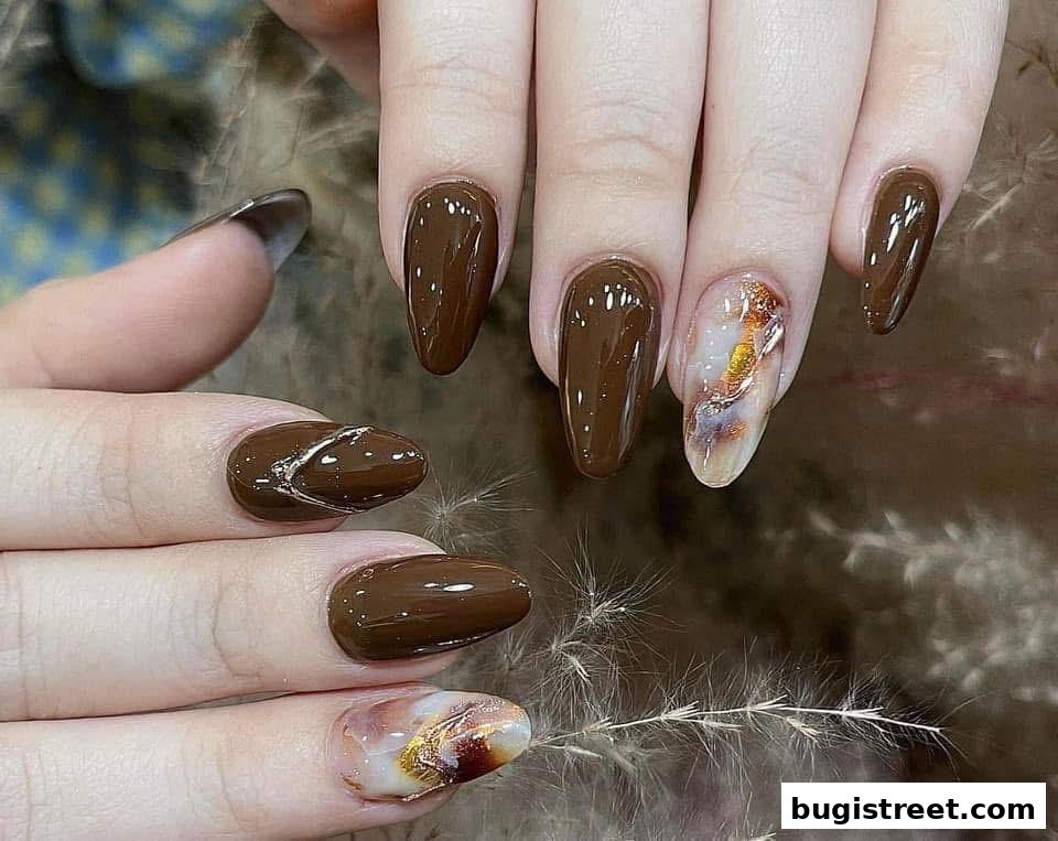Close-up of hands with beautifully manicured nails in a rich brown shade with artistic accents.