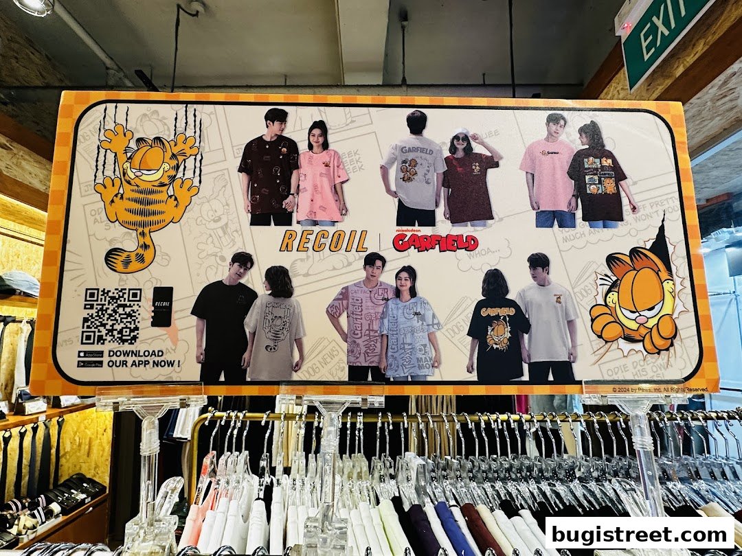 A display board showcasing Garfield-themed t-shirts from Recoil, featuring models wearing the apparel.