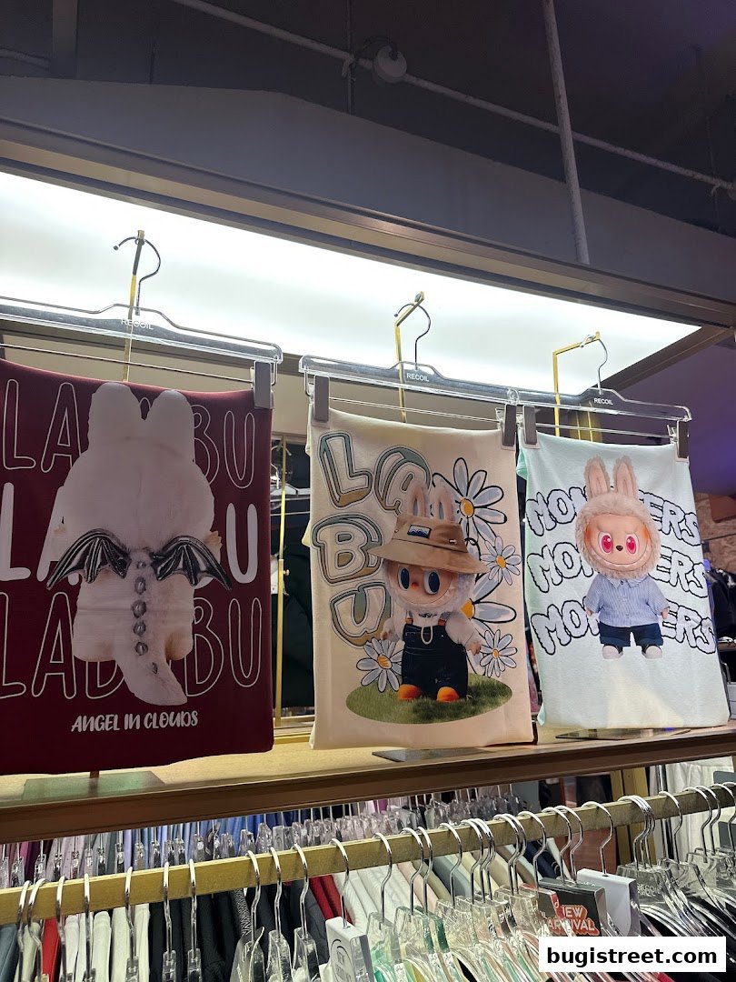 Three graphic tees with cute cartoon characters displayed on hangers in a retail store.