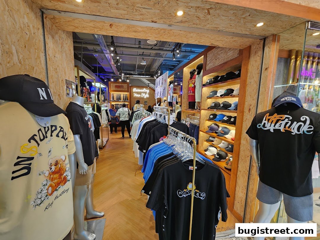 Mannequins display graphic t-shirts and caps inside a trendy clothing store.