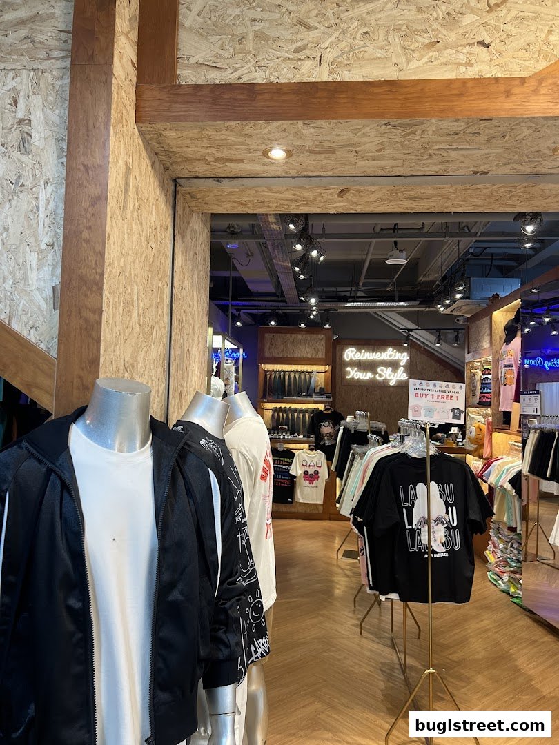 Mannequins display trendy apparel inside a modern clothing store with racks of t-shirts.